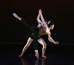 Dance partnering – a male dancer assists a female dancer in performing an arabesque, as part of a classical pas de deux.