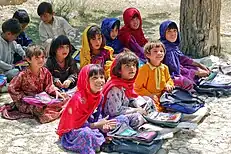 Photo of primary school children sitting in an orchard