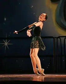 A dancer performs a "toe rise", in which she rises from a kneeling position to a standing position on the tops of her feet.